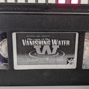 Black VHS cassette with a printed The Case of the Vanishing Water label