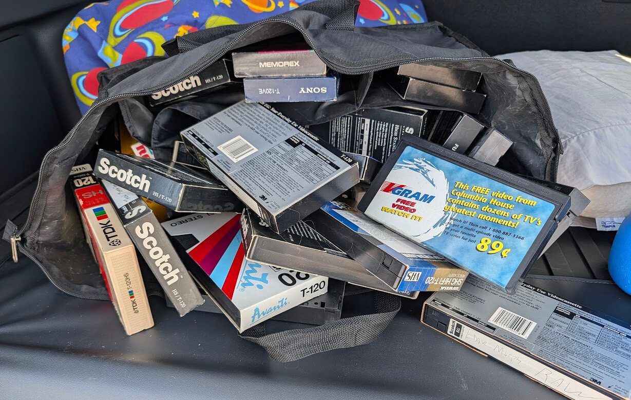 Open bag full of VHS tapes including handwritten labels and Columbia House video