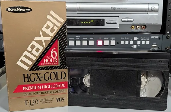 Unlabeled Maxell VHS beside its HGX-Gold T-120 sleeve.