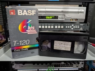 Full VHS tape with handwritten children’s-program titles beside a worn BASF T-120 sleeve.