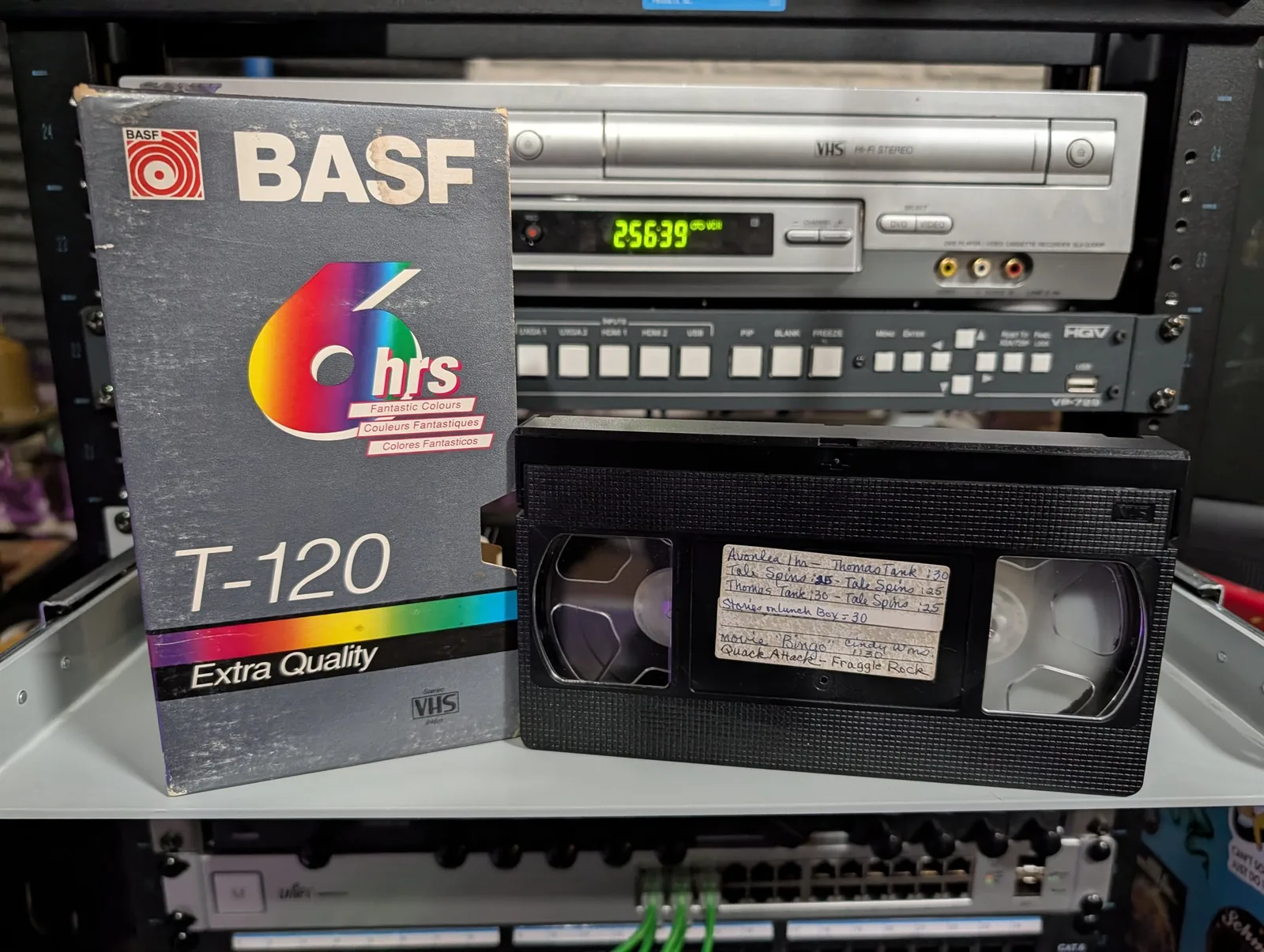Full VHS tape with handwritten children’s-program titles beside a worn BASF T-120 sleeve.