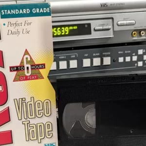 VHS cassette beside a T-120H Standard Grade sleeve; both extend below the cropped frame.