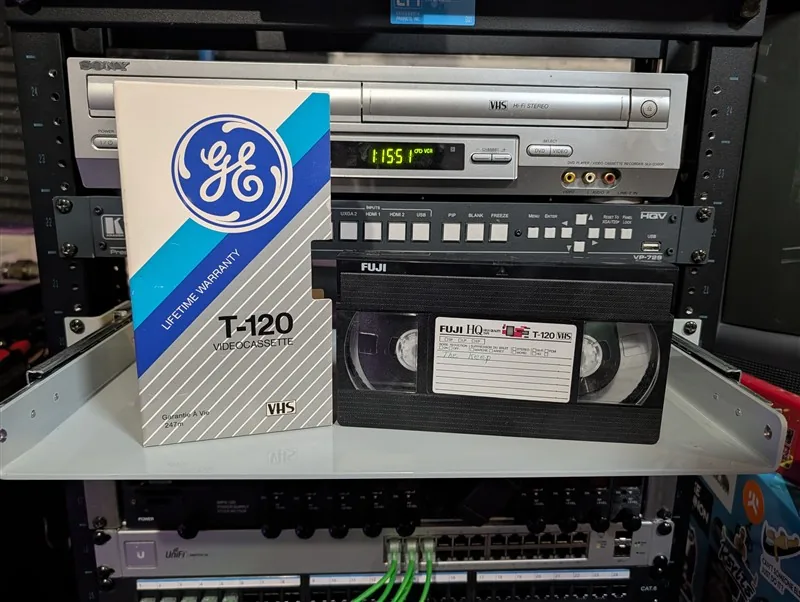 Fuji HQ T-120 VHS with faint handwritten label beside a mismatched GE T-120 Lifetime Warranty sleeve.