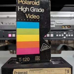 Polaroid High Grade sleeve standing above a tape labeled The Mighty Ducks.