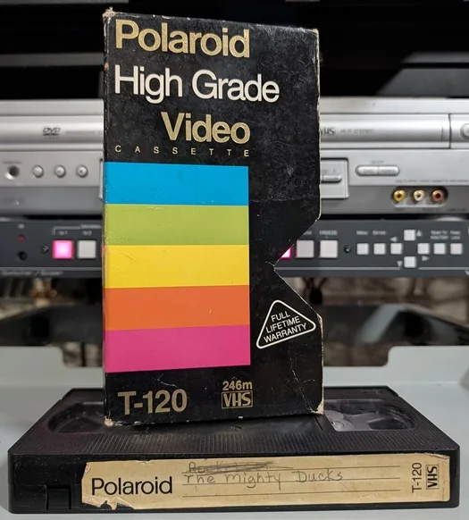 Polaroid High Grade sleeve standing above a tape labeled The Mighty Ducks.