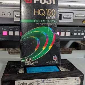 Polaroid VHS tape with worn Fuji sleeve and crossed-out handwritten label
